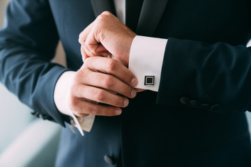 Close-up groom hands puts on cufflinks. Elegant gentleman clothers, white shirt