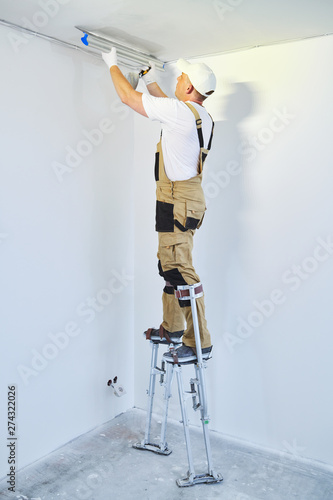 Painter In Stilts With Putty Knife Plasterer Smoothing