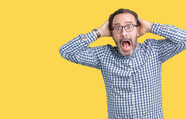 Poster - Handsome middle age elegant senior man wearing glasses over isolated background Crazy and scared with hands on head, afraid and surprised of shock with open mouth