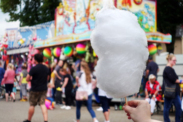 Wall Mural - amusement park eating white cotton candy. enjoying a day at amusement park with fresh cotton candy in hand