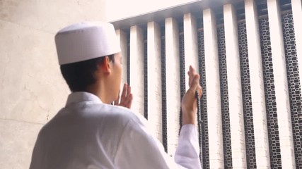 Wall Mural - Side view of young muslim man praying in Istiqlal Mosque during ramadan.