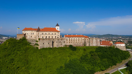 Wall Mural - Picturesque view to the Palanok Castle with the red roofs under the blue sky in Mukachevo, Transcarpathian region in Ukraine. Horizontal outdoors shot.