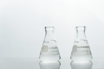 two glass science laboratory flask with clear water on white background