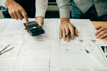 Architects or engineering working with blueprints and discussing project together at the meeting in the office.