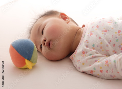 ベッドの上にボールを遊んでいる可愛い赤ちゃん Buy This Stock