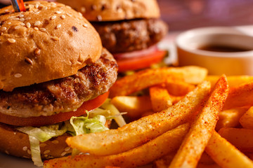 Clos up Two mini burgers in the restaurant. Sesame bun, meat Patty, tomato, lettuce and pickle. Tasty Served with French fries