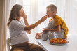 © Alena Ozerova - Pregnant mom with kid eating fruits together in the kitchen