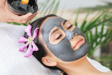 Beautiful Asian woman undergoing treatment with facial mask in beauty salon