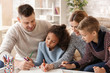 © Pixel-Shot - Happy couple with little adopted children drawing at home
