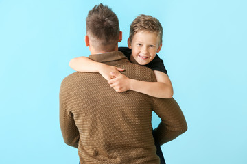 Wall Mural - Happy man with little adopted boy on color background