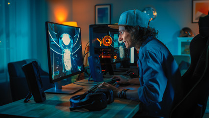 Wall Mural - Professional Gamer Playing First-Person Shooter Online Video Game on His Powerful Personal Computer. Room and PC have Colorful Neon Led Lights. Young Man is Wearing a Cap. Cozy Evening at Home.