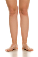 Wall Mural - Front view of female barefoot legs on white background