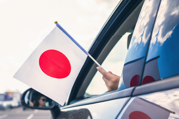 Wall Mural - Woman or Girl Holding Japan, Flag from the open car window