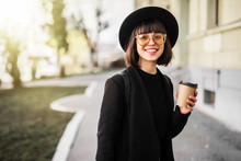 Stylish Happy Young Woman Holds Coffee To Go In The Street