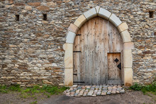 Ancient Wooden Door In Old Stone Castle Wall.