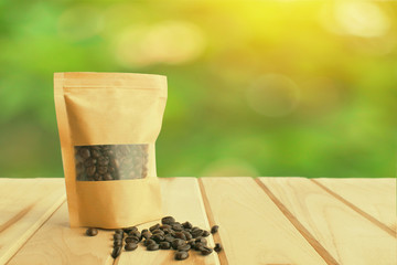 coffee beans are packed in paper bags on wood table green bokeh background.