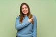 © luismolinero - Young girl over green wall pointing to the side to present a product