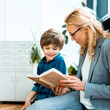 © LIGHTFIELD STUDIOS - attractive woman in glasses sitting and reading book with happy kid