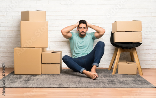 Платно  Handsome young man moving in new home among boxes with surprise facial expressio