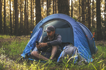 travel blogger man making social video story in a camping tent tourist boy communicate with smartpho