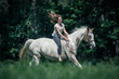 Ein junges Mädchen reitet ohne Sattel am langen Zügel mit ihrem Schecke Pferd über die Wiese, Pferde