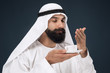 © master1305 - Half-length portrait of arabian saudi businessman on dark blue studio background. Young male model standing and drinking coffee or tea. Concept of business, finance, facial expression, human emotions.