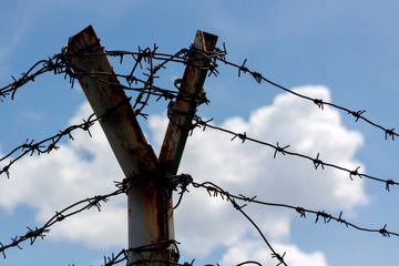 barbed wire fence with blue sky and clouds background.