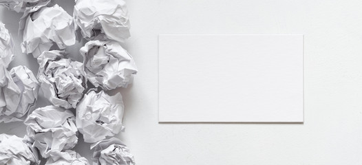 Canvas Print - Business idea. Flat lay of blank card and crumpled paper ball pile on white background. Copy space.