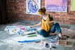 © golubovy - Modern art school. Female artist sitting on floor, painting abstract artworks. Creative workplace.