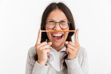 Sticker - Excited emotional young school girl isolated over white wall background holding pencil.