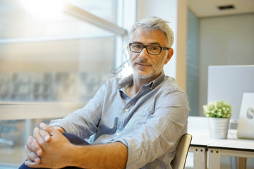 Portrait of smart casual businessman looking at camera in contemporary office