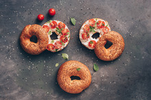 Homemade Bagel Sandwich With Soft Cheese, Cherry Tomatoes And Basil Sprinkled With Sesame And Flax Seeds, Dark Rustic Background. Overhead View, Copy Space.