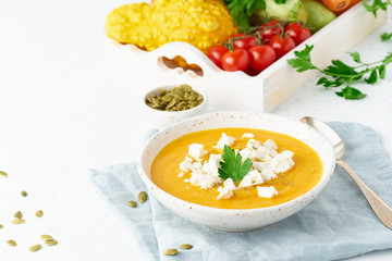 Wall Mural - Pumpkin cream soup with feta cheese, autumn homemade food, white background, closeup, copy space