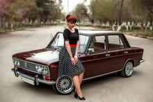 Portrait Of A Caucasian Beautiful Young Girl In A Black Vintage Dress, Posing Near A Vintage Car