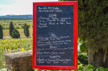 French menu propped on a chair with vineyards in the background