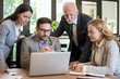 © Bojan - Group of business people looking at laptop computer during meeting in office