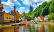Cesky Krumlov (Czech Krumlov), Czech Republic. Antique town on river Vltava. Picturesque landscape with cosy colourful houses on banks among green trees. Sunny summer day with blue sky and clouds.