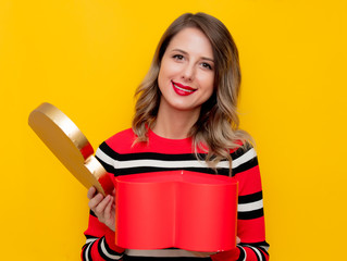 Wall Mural - Young woman in red striped sweater with heart shape box