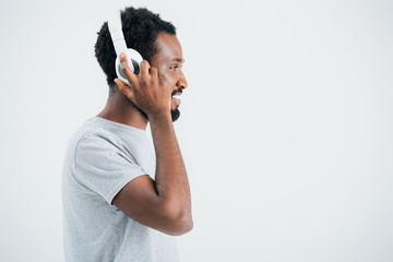 Wall Mural - smiling african american man listening music with headphones, isolated on grey