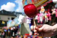 Sweet Candy Apple On County Fair Or Festival. Red Candy Apple Covered In Red Caramel, At Holiday Vacation Event Or Amusement Park