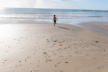 Child playing on the beach. Small child having fun on the sands and beach water.