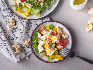 Light breakfast from Caesar salad on two tarekkas, standing on a cotton napkin with a pattern, cutlery and sauceboat with salad dressing, cutlery