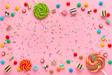 Festive Wreath Background With Assortment Of Colourful Caramel Candies, Lollipops And Sprinkles Over Pink