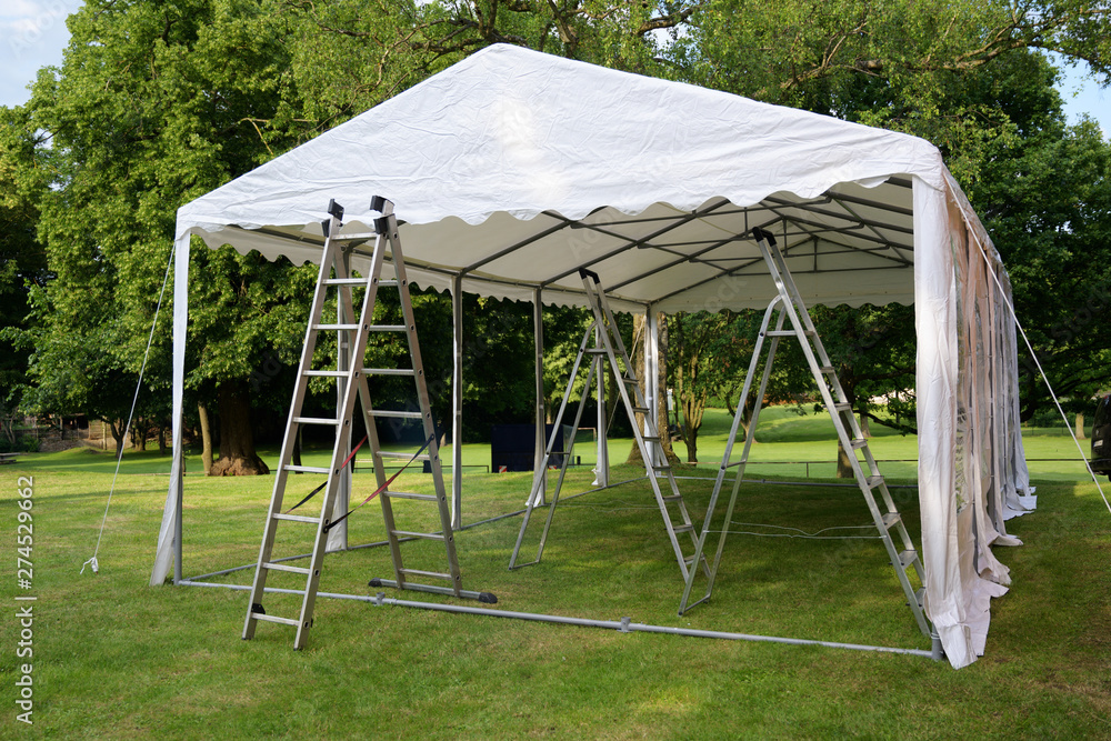 event tent set up  with ladders on the lawn in a park for a summer party or wedding - obrazy, fototapety, plakaty 