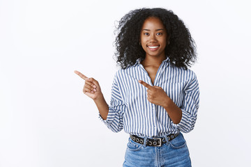 Charming friendly-looking smiling african-american assistant help you make choice grinning pleasant pointing left index finger promoting copy space product, standing joyfully upbeat white background