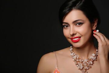 Poster - Beautiful young woman with elegant jewelry on dark background. Space for text