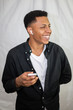 © pablobenii - Happy African American young handsome man with wireless earphones in black shirt holding smartphone and laughing