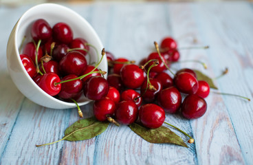 Wall Mural - Fresh red cherries in a white plate on a light blue background, space for text, concept of natural fresh vegetarian food