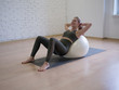 © junky_jess - Woman makes abs exercise using big fitness ball in pilates studio, loft background