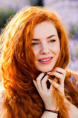 Summer portrait of a beautiful girl with long curly red hair. woman with long hair. European girl in lavander field.